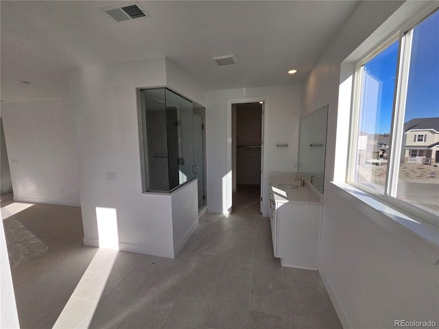 hallway with a healthy amount of sunlight, a sink, visible vents, and baseboards