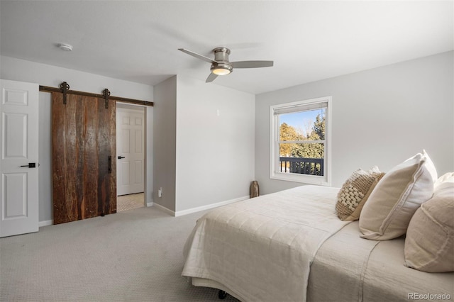 carpeted bedroom featuring a barn door and ceiling fan