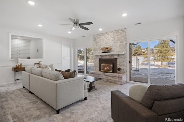 living room with light carpet, a fireplace, and ceiling fan