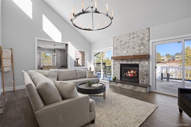 living room with dark hardwood / wood-style flooring, a fireplace, high vaulted ceiling, and a chandelier