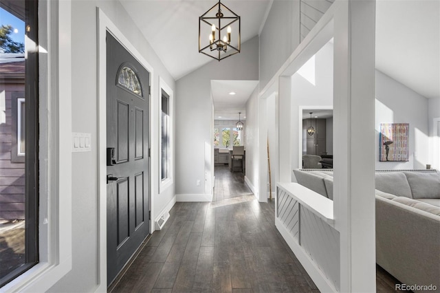 foyer featuring baseboards, lofted ceiling, dark wood-style floors, and a chandelier
