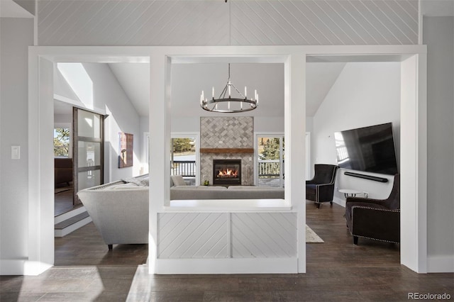 living area with an inviting chandelier, dark wood-style floors, lofted ceiling, and a tile fireplace
