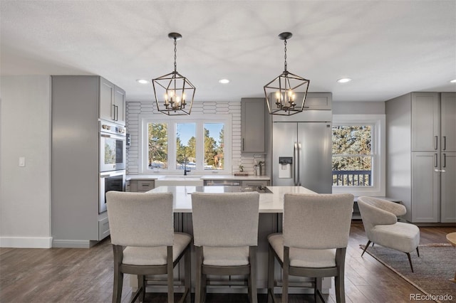 kitchen with light countertops, gray cabinets, a chandelier, and stainless steel appliances