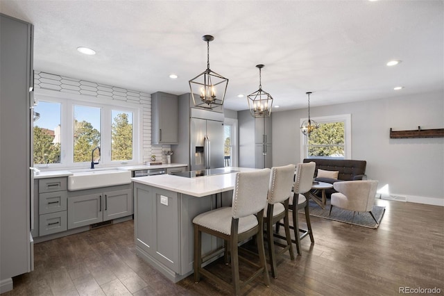 kitchen with built in refrigerator, a sink, gray cabinets, and dark wood finished floors