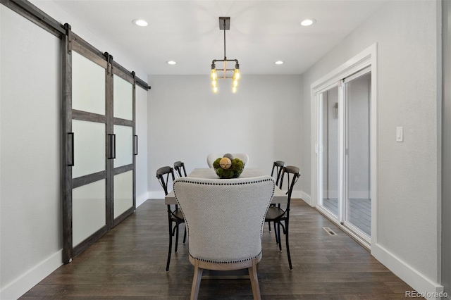 dining space featuring a barn door, dark wood finished floors, recessed lighting, baseboards, and visible vents