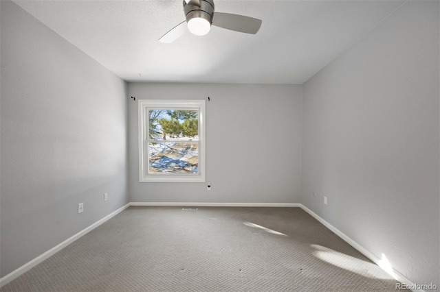 carpeted empty room with ceiling fan and baseboards