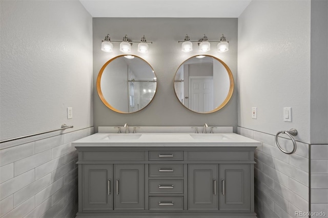 bathroom featuring a sink, tile walls, and double vanity