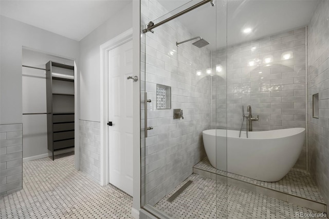 full bath with a freestanding tub, tile walls, a shower stall, and tile patterned floors