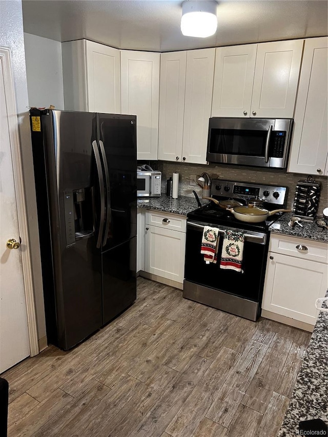 kitchen featuring appliances with stainless steel finishes, backsplash, white cabinets, and light hardwood / wood-style floors