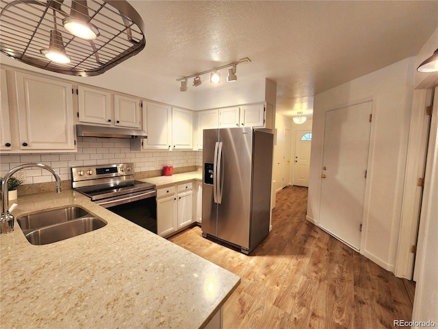 154 Fawn Ct, Silverthorne, CO 80443 - kitchen with appliances with stainless steel finishes, a sink, under cabinet range hood, light wood finished floors, and white cabinetry