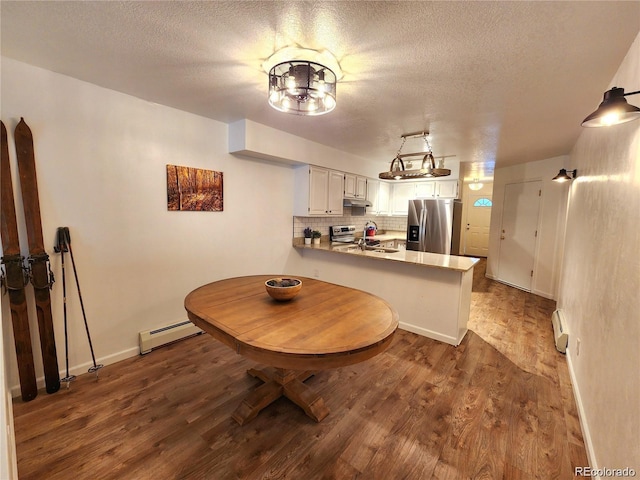 154 Fawn Ct, Silverthorne, CO 80443 - kitchen featuring stainless steel fridge, a baseboard heating unit, a peninsula, a textured ceiling, and dark wood-style floors