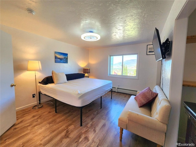 154 Fawn Ct, Silverthorne, CO 80443 - bedroom featuring baseboard heating, a textured ceiling, wood finished floors, and baseboards