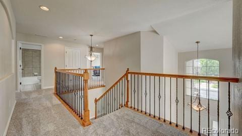 hallway with carpet floors, an inviting chandelier, and lofted ceiling