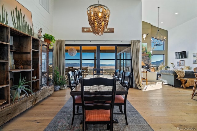 dining space with wood finished floors, a towering ceiling, and an inviting chandelier