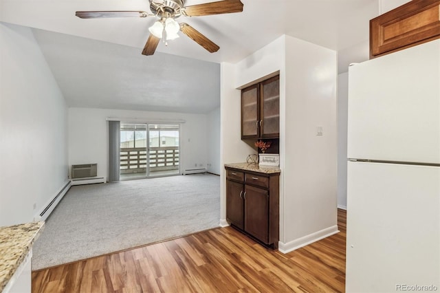 kitchen featuring lofted ceiling, freestanding refrigerator, light stone countertops, light wood finished floors, and glass insert cabinets