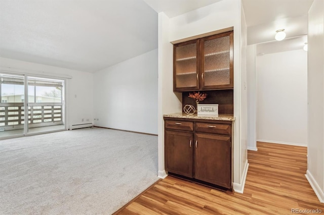 interior space featuring a baseboard heating unit, light carpet, light wood-style floors, and baseboards