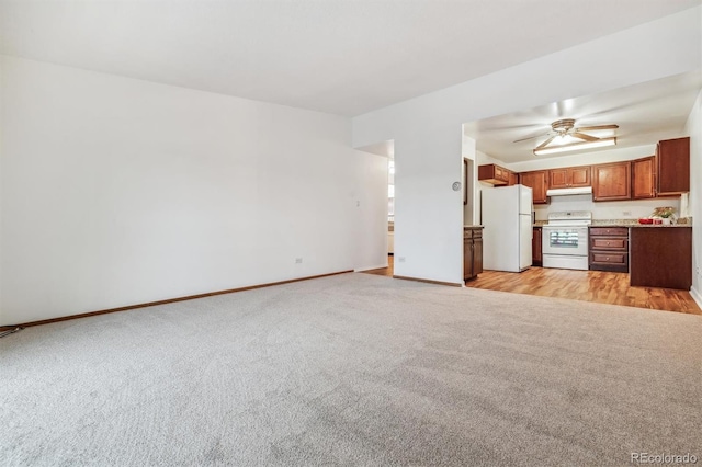 unfurnished living room with light carpet, a ceiling fan, and baseboards