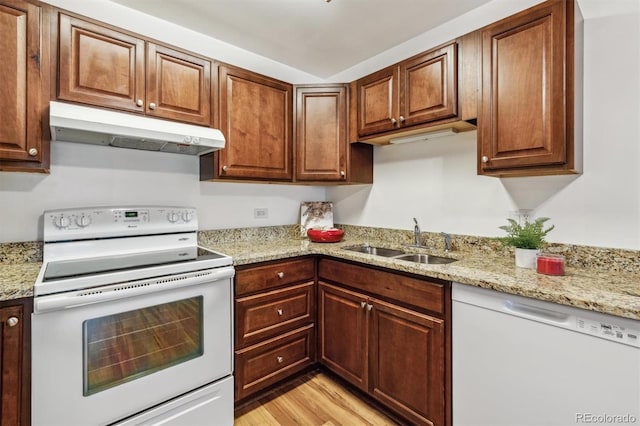 kitchen featuring a sink, light stone countertops, light wood-type flooring, white appliances, and under cabinet range hood