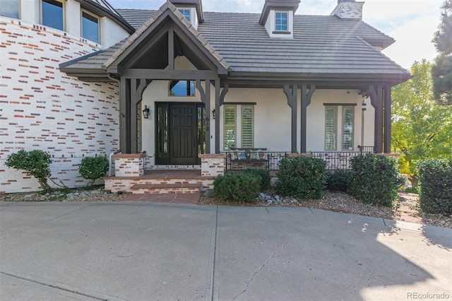 618 Fairchild Dr, Highlands Ranch, CO 80126 - property entrance featuring stucco siding, a chimney, a tiled roof, and covered porch