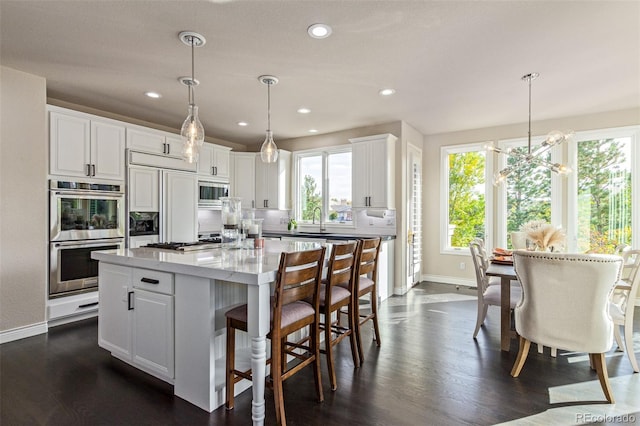 618 Fairchild Dr, Highlands Ranch, CO 80126 - kitchen featuring a sink, built in appliances, baseboards, white cabinetry, and dark wood-style floors