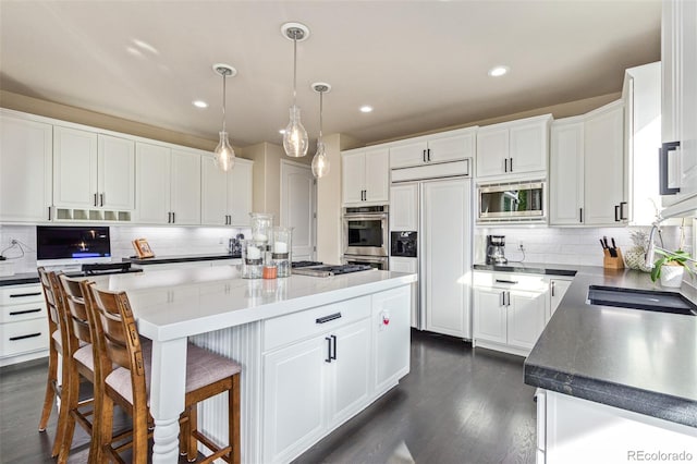 618 Fairchild Dr, Highlands Ranch, CO 80126 - kitchen with white cabinets, built in appliances, a kitchen island, and backsplash