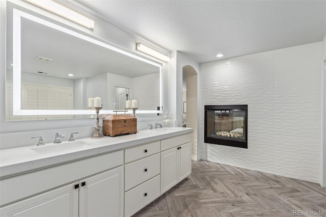 618 Fairchild Dr, Highlands Ranch, CO 80126 - full bath with a glass covered fireplace, a sink, visible vents, and recessed lighting