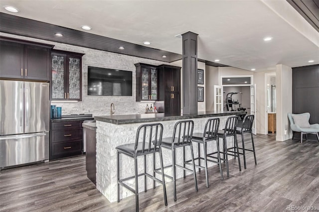 618 Fairchild Dr, Highlands Ranch, CO 80126 - kitchen featuring a kitchen breakfast bar, glass insert cabinets, freestanding refrigerator, dark wood-style flooring, and ornate columns