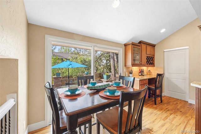 dining room featuring light wood-type flooring and vaulted ceiling