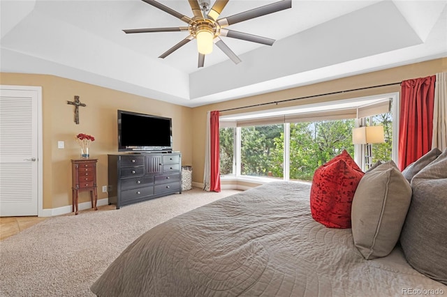 carpeted bedroom featuring multiple windows, a raised ceiling, and ceiling fan