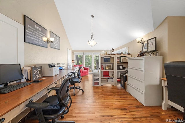 office space featuring lofted ceiling, light wood-type flooring, and an inviting chandelier