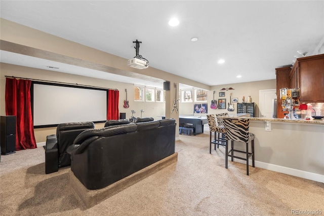 home theater room featuring bar area and light colored carpet