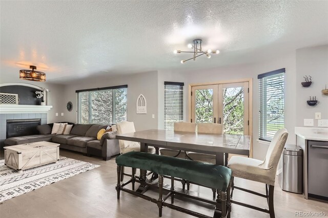 3805 E 106th Ave, Thornton, CO 80233 - dining area featuring french doors, a textured ceiling, a fireplace, a chandelier, and light wood finished floors