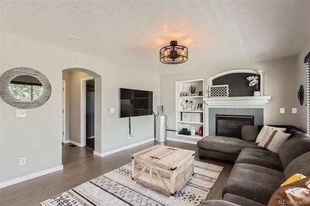 3805 E 106th Ave, Thornton, CO 80233 - living room with baseboards, dark wood finished floors, built in shelves, arched walkways, and a fireplace