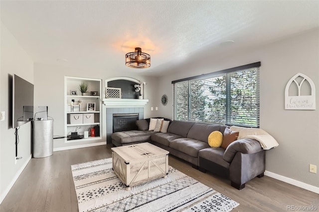 3805 E 106th Ave, Thornton, CO 80233 - living area with baseboards, built in shelves, a chandelier, wood finished floors, and a fireplace