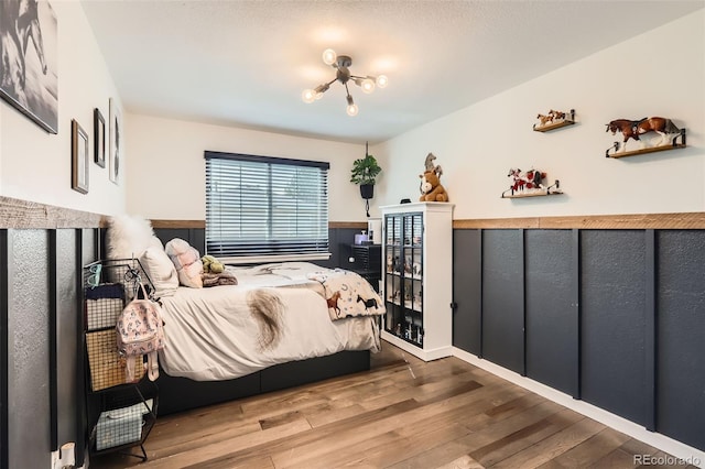 3805 E 106th Ave, Thornton, CO 80233 - bedroom featuring a notable chandelier, a wainscoted wall, and wood finished floors