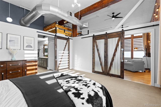 carpeted bedroom with beamed ceiling, a barn door, a towering ceiling, and connected bathroom