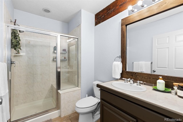 bathroom with tile patterned floors, vanity, toilet, and a shower with door