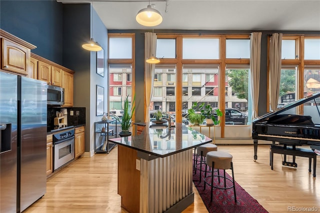 kitchen featuring a breakfast bar area, dark stone countertops, light hardwood / wood-style floors, a kitchen island, and stainless steel appliances