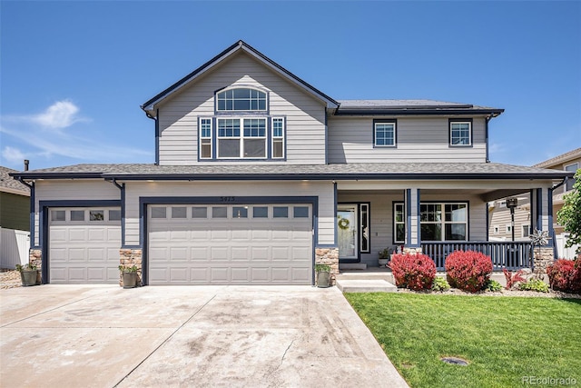 view of front facade with a front lawn, driveway, covered porch, an attached garage, and stone siding