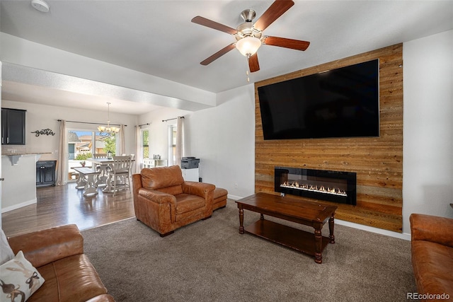 living area with a fireplace, a ceiling fan, a chandelier, and baseboards