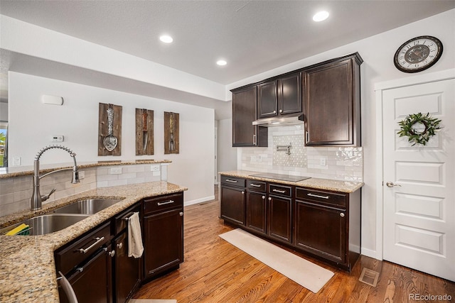 kitchen with a sink, light wood-type flooring, light stone countertops, tasteful backsplash, and recessed lighting