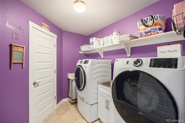 clothes washing area featuring washer and dryer, cabinet space, and light tile patterned floors