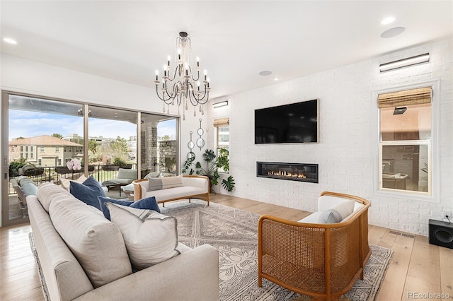 7033 E Lake Cir, Centennial, CO 80111 - living room with hardwood / wood-style floors, a healthy amount of sunlight, visible vents, a chandelier, and a glass covered fireplace