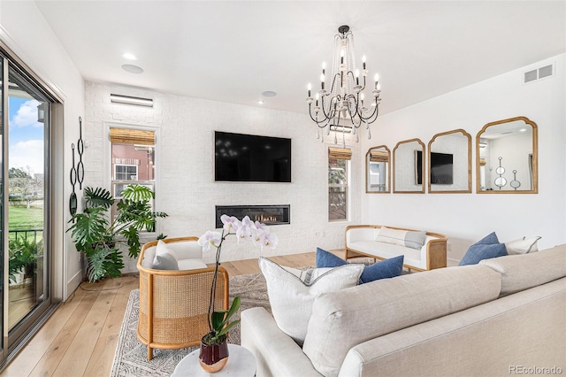 7033 E Lake Cir, Centennial, CO 80111 - living area with an inviting chandelier, a glass covered fireplace, visible vents, and light wood-style floors
