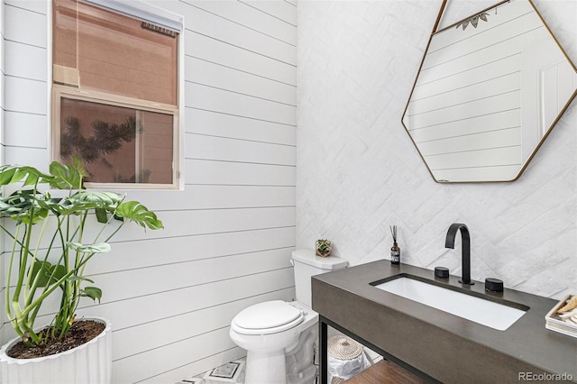 7033 E Lake Cir, Centennial, CO 80111 - bathroom featuring toilet, decorative backsplash, wooden walls, and a sink