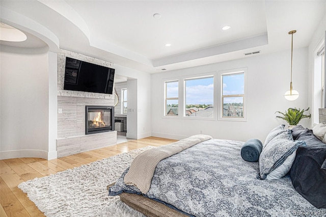 7033 E Lake Cir, Centennial, CO 80111 - bedroom featuring baseboards, a tray ceiling, visible vents, and light wood-style flooring