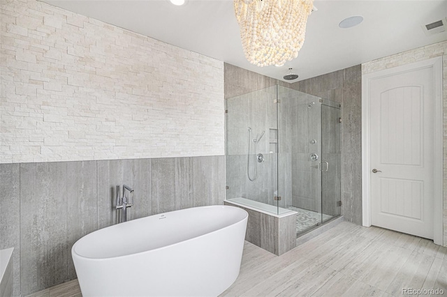 7033 E Lake Cir, Centennial, CO 80111 - full bath with an inviting chandelier, wood finished floors, a stall shower, a soaking tub, and visible vents