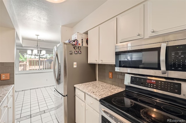 2896 W 119th Ave, Westminster, CO 80234 - kitchen featuring stainless steel appliances, white cabinets, a chandelier, light tile patterned floors, and tasteful backsplash