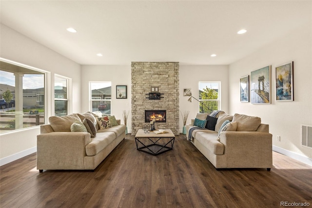 living room with a stone fireplace and dark hardwood / wood-style flooring