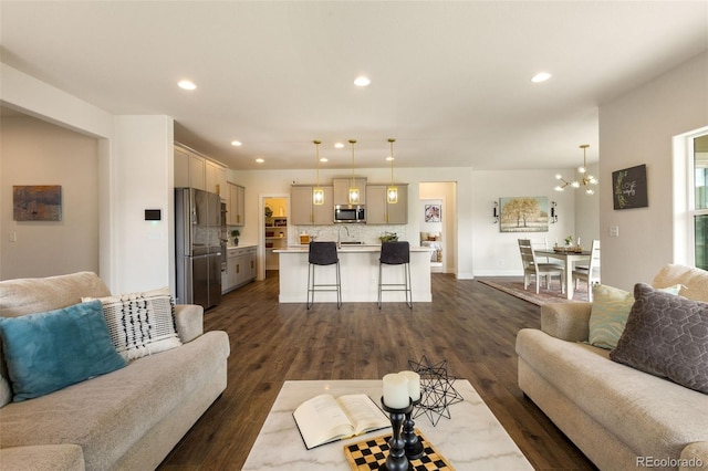 living room with sink, an inviting chandelier, and dark hardwood / wood-style flooring